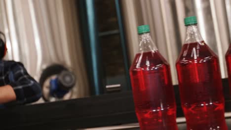 Worker-checking-juice-bottles-on-production-line