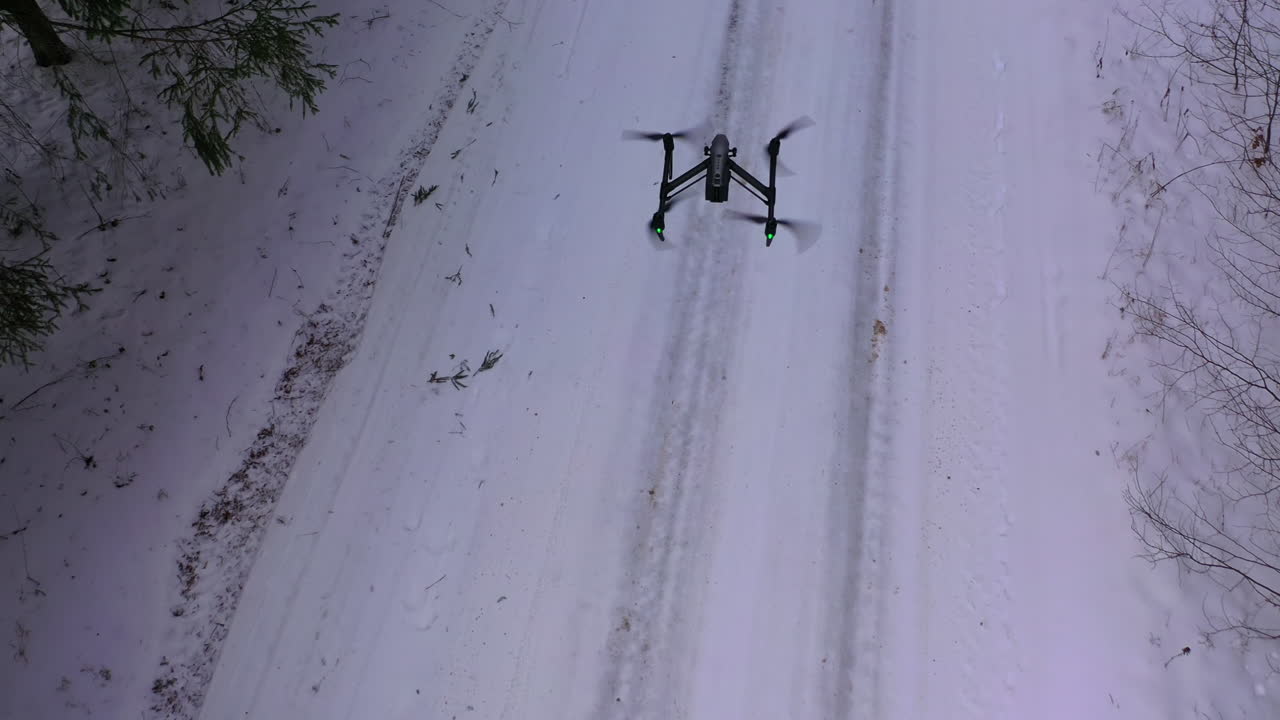 Drone flying above forest covered with snow. Flying drone in action on the winter snow landscape background