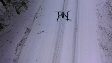 Drone flying above forest covered with snow. Flying drone in action on the winter snow landscape background