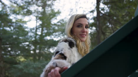 stylish young woman smiles as she walks on to an overlook in the forest