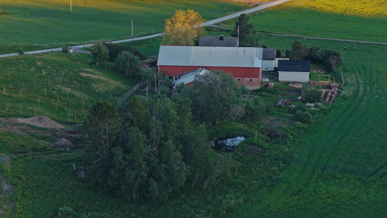 Traditionel rødmalt bondegård omgivet af grønne landbrugsmarker i Norge. - luftfoto.