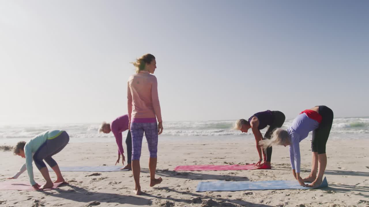 Athletic women performing yoga in the beach