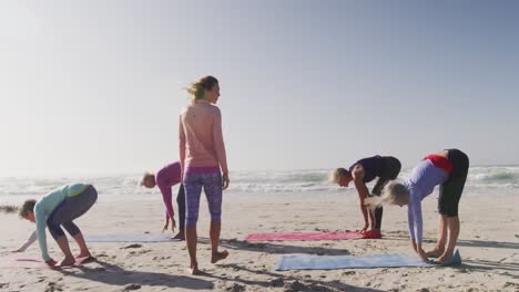 athletic women performing yoga in the beach