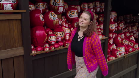 woman tourist walking in katsuo-ji temple surrounded with daruma dolls in osaka, japan - tracking shot