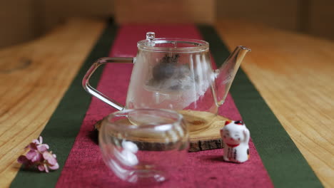 tetera de vidrio y taza puesta en una mesa de madera