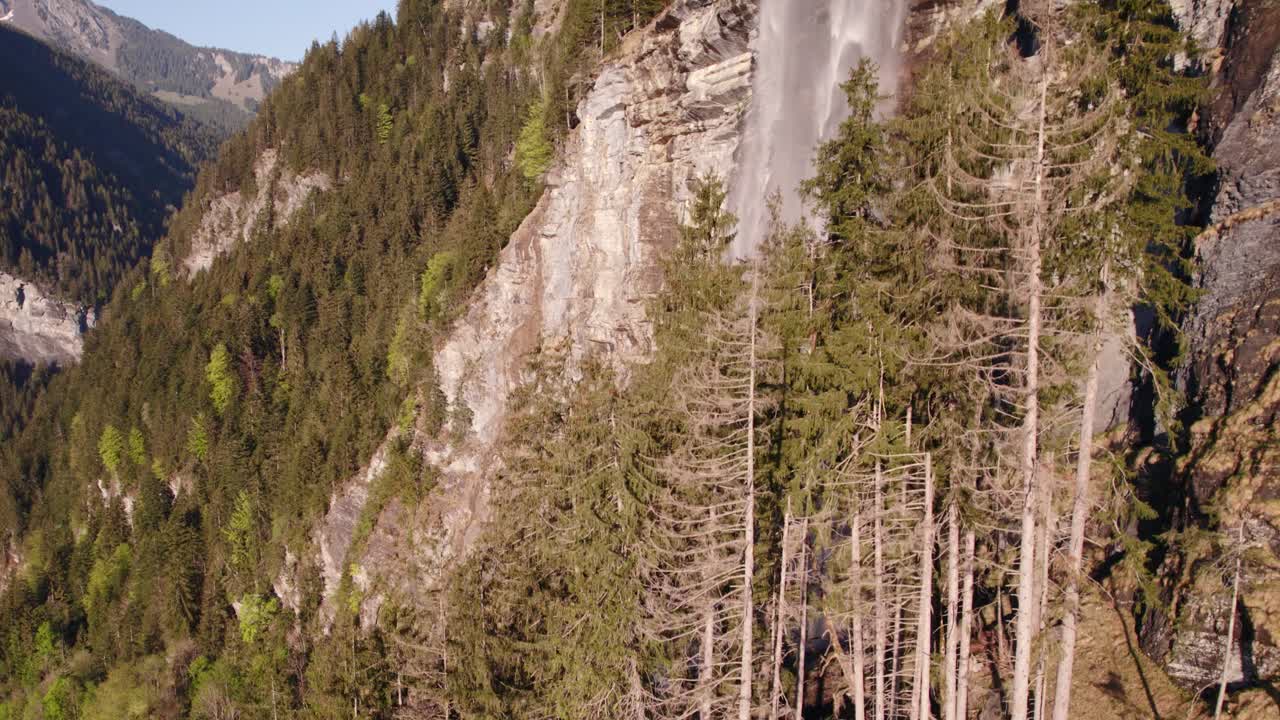 Riprese aeree con drone che si alza rivelando una pittoresca cascata da sogno a Grindelwald nelle Alpi svizzere.