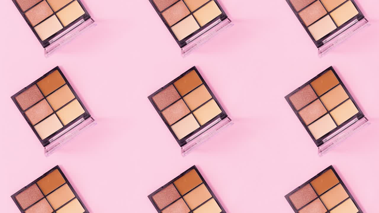 Creative make up pattern made of eye shadow palettes rotating on pink background. Stop motion
