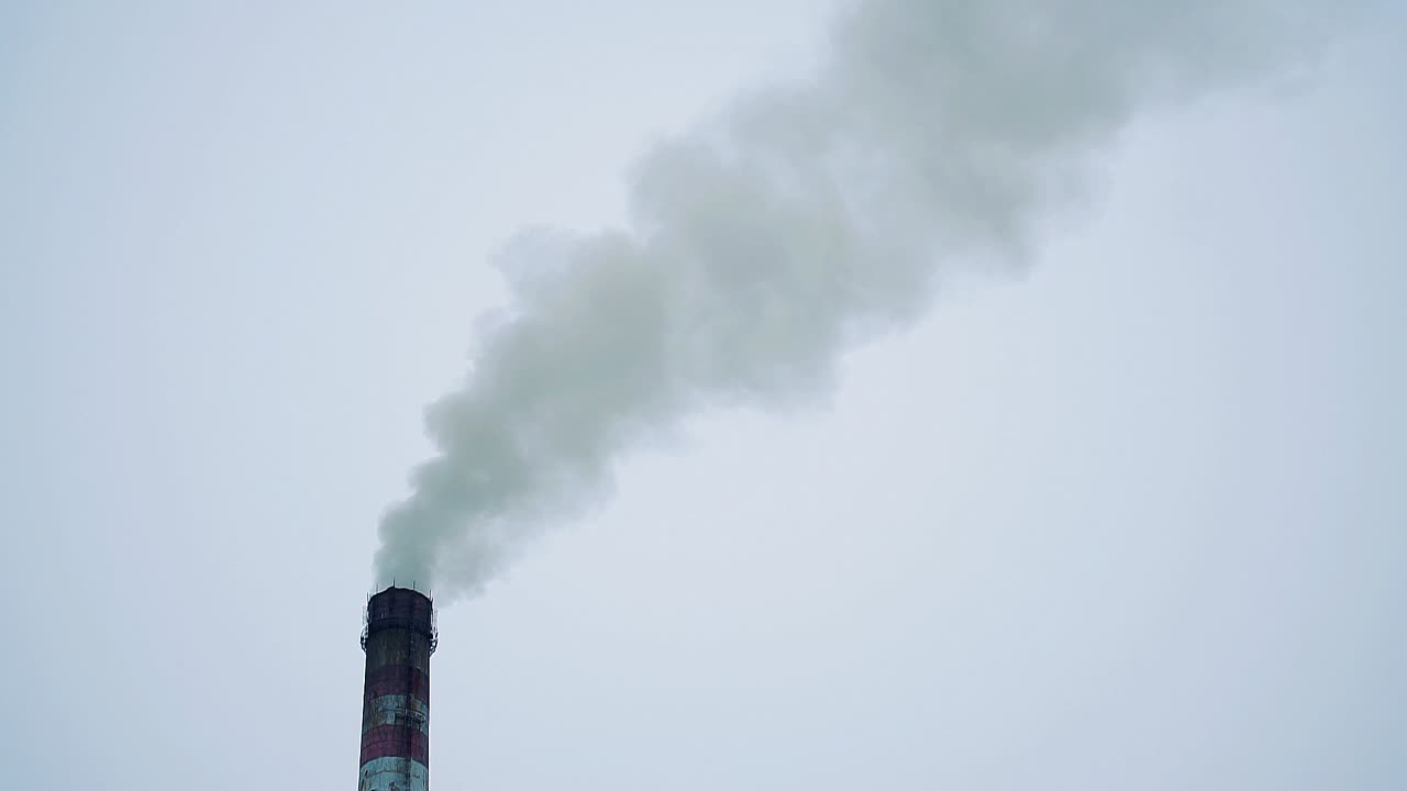 smoke from a large pipe of a thermal power plant against a gray cloudy sky. Industrial zone