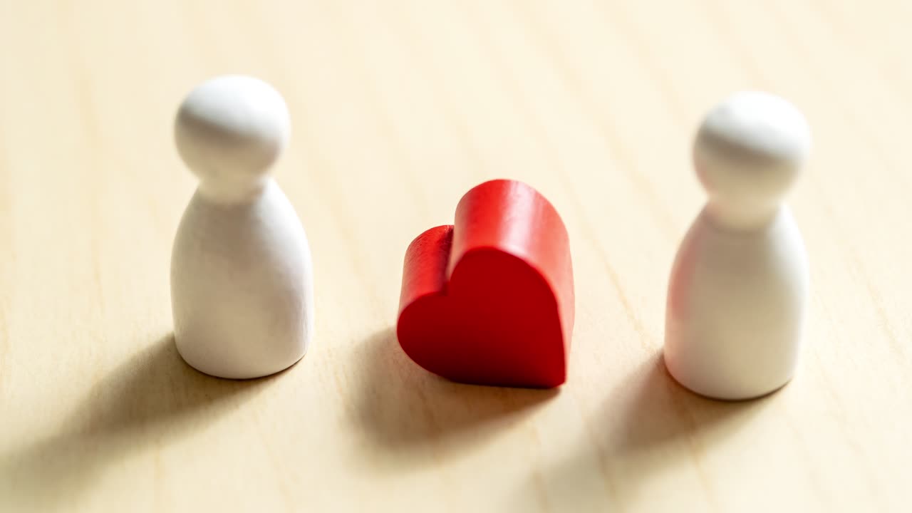 Two figurines and a heart symbolize connection exploring emotions in a minimalist environment.