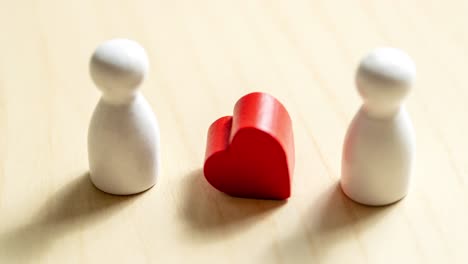 Two figurines and a heart symbolize connection exploring emotions in a minimalist environment.