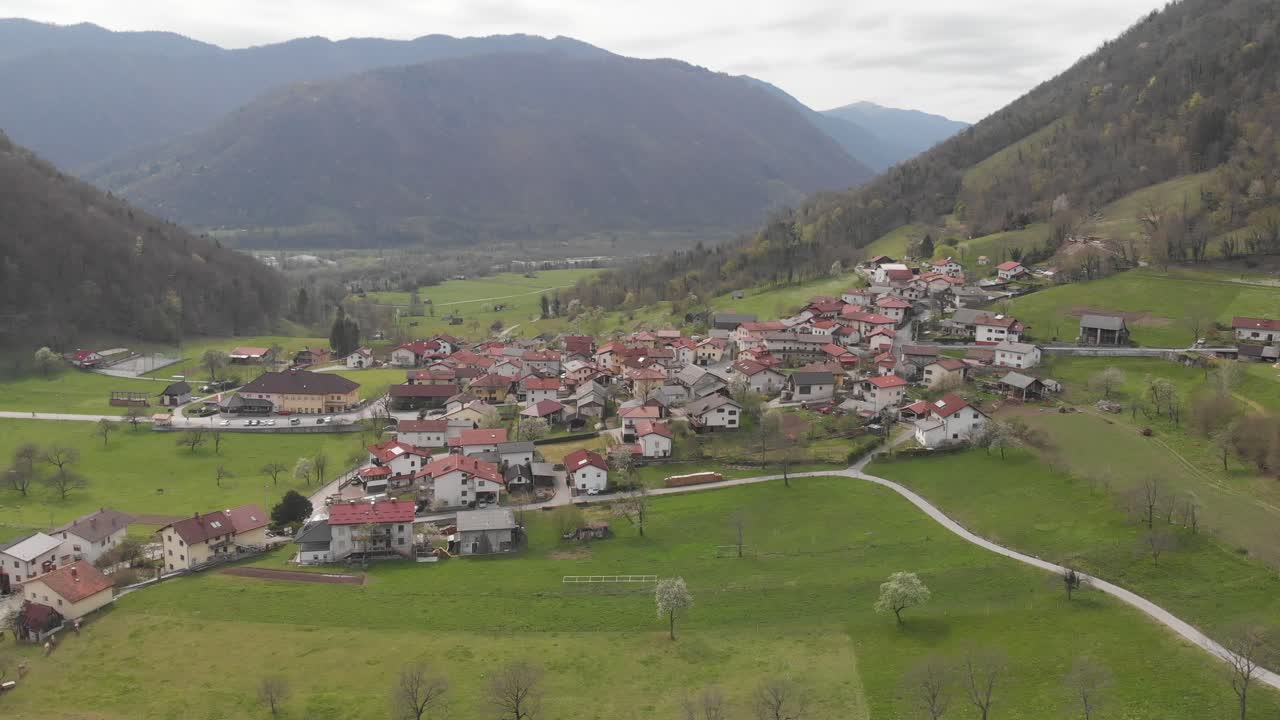 drone volando hacia un pueblo en el campo rural de eslovenia, día nublado de primavera temprana