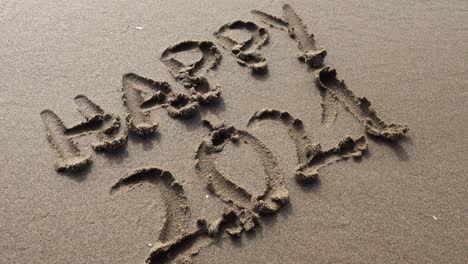 아름다운 조명으로 일몰의 모래에 손으로 행복한 2021년을 쓰세요