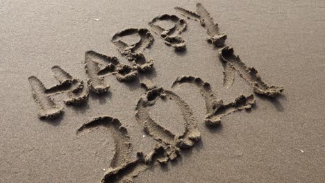 hand writing happy 2021 in the sand at sunset with beautiful lighting