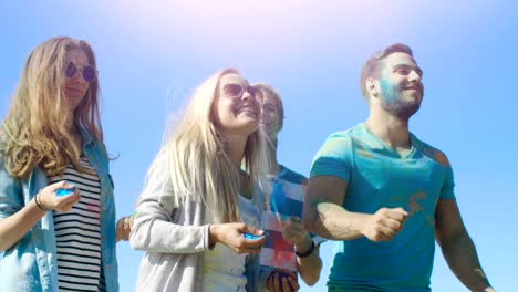 un grupo multiétnico de jóvenes diversos bailando en celebración del festival de holi. se divierten enormemente en este día soleado.
