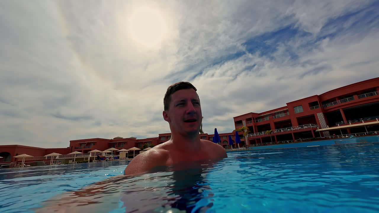 vista en cámara lenta de un turista explorando una piscina en un complejo de lujo