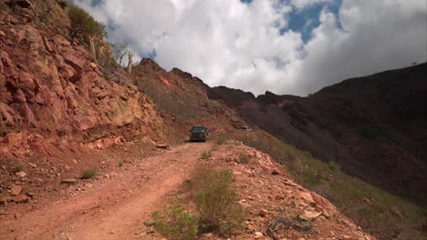 cars driving off-road on a ridge in the rocky orange mountains landscape