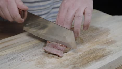 chef slicing beef cut on wooden board with a chefes axe