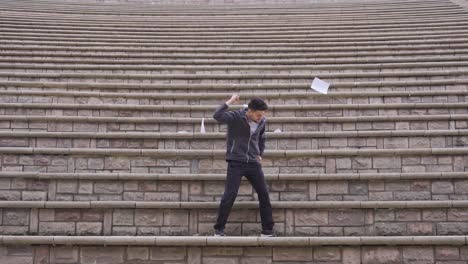 the young man rejoices and merrily tosses the papers into the air.