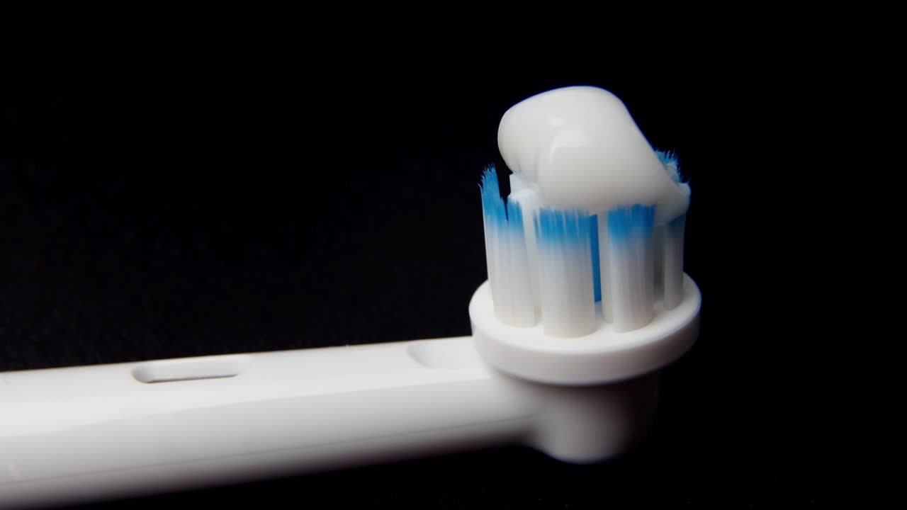macro-video del trabajo del cepillo eléctrico y la aplicación de la pasta de dientes. un primer plano muestra la cabeza de la boquilla, cuyas vellosidades se mueven rápidamente. concepto de higiene bucal