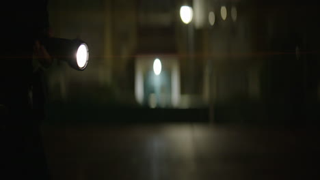 Person with Flashlight in Dark Building