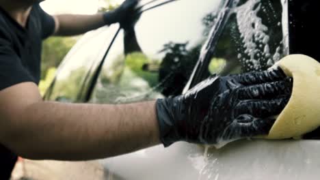 Nahaufnahme-Eines-Mannes,-Der-Ein-Auto-Mit-Schwarzen-Handschuhen-Mit-Shampoo-Und-Schwamm-Wäscht