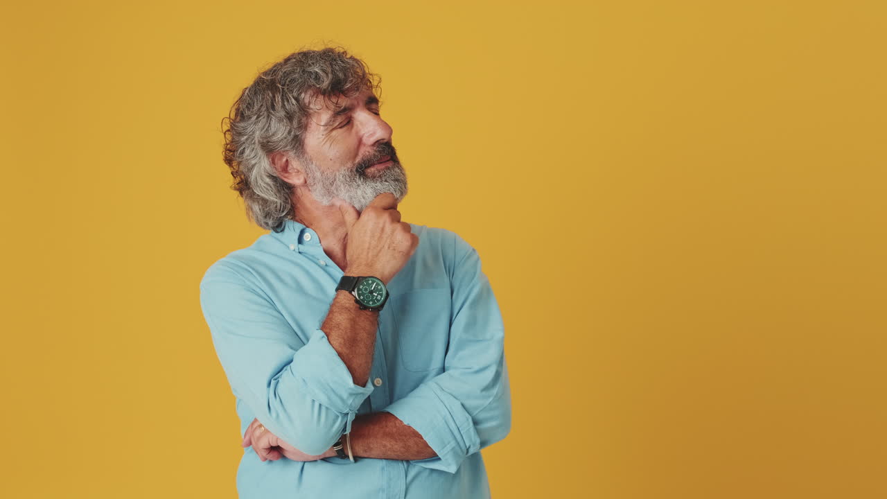 Thoughtful Mature Man Pondering and Looking Up on Yellow Background
