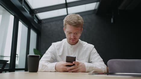 businessman in lunch in cafe sitting at table and using smartphone reading news in internet viewing social media