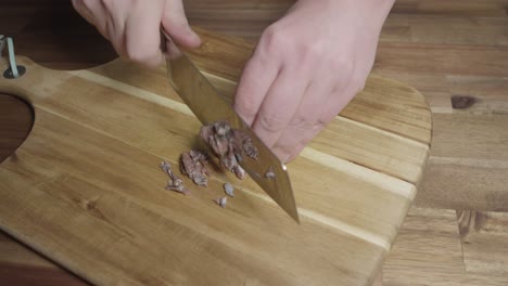 chef chopping anchovies with a knife on a cutting board