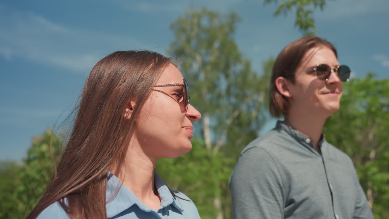 trabajo en equipo alegre y soleado, profesionales informales caminando juntos bajo un cielo azul despejado y un dosel frondoso, amigos y compañeros de trabajo participando en una conversación relajada a lo largo de un sendero iluminado por el sol con una exuberante vegetación