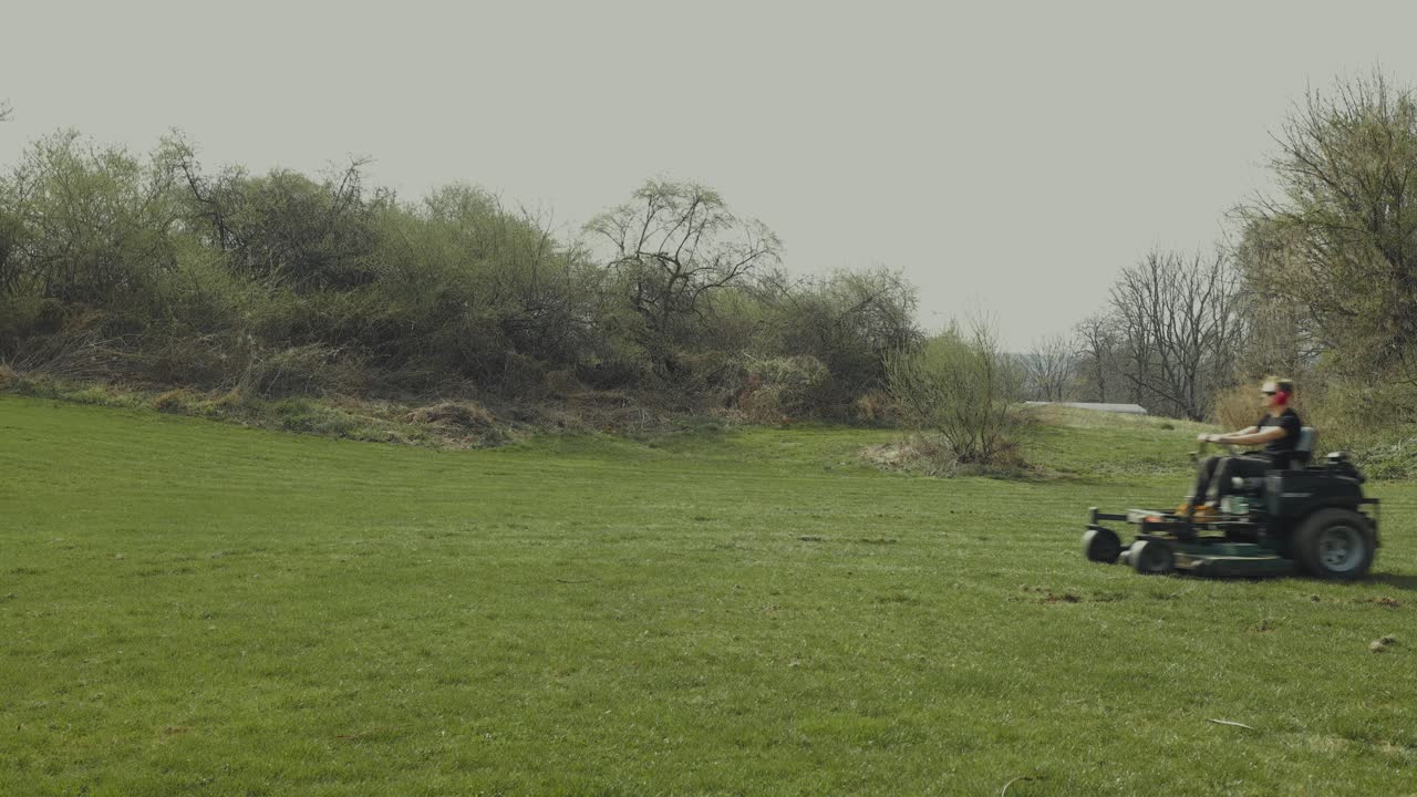 A man rides by on a lawn mower during a cloudy day