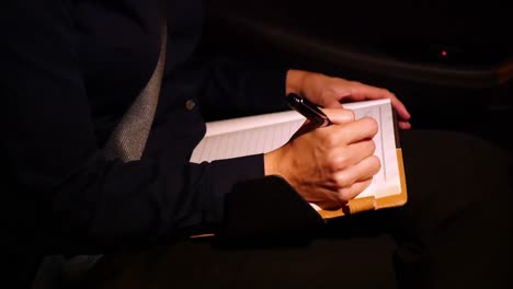 businesswoman writing in diary while travelling in car