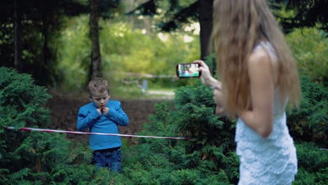 young mother takes pictures of her son on a smartphone