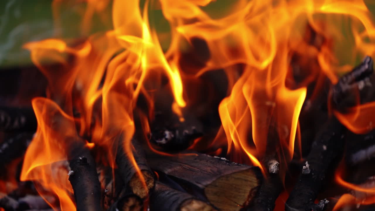 Wooden logs in bright flame. Wood burning in fire. Orange flame over the smoldering logs. Close-up. Slow motion.