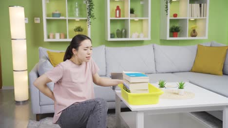 무거운 물건을 들고 다니는 젊은 아시아 여성은 헤르니아와 신체 조직 손상을 초래합니다.