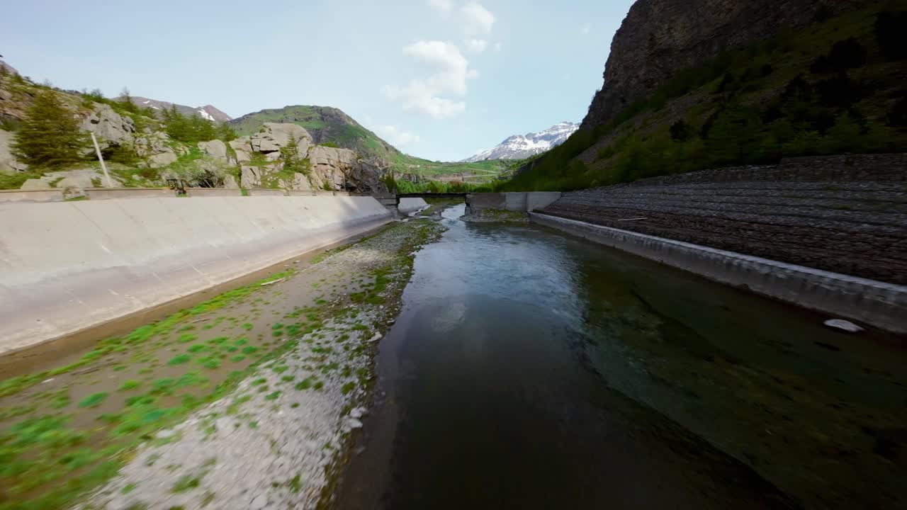 drone fpv volando a alta velocidad sobre el río y la carretera asfaltada de mont cenis