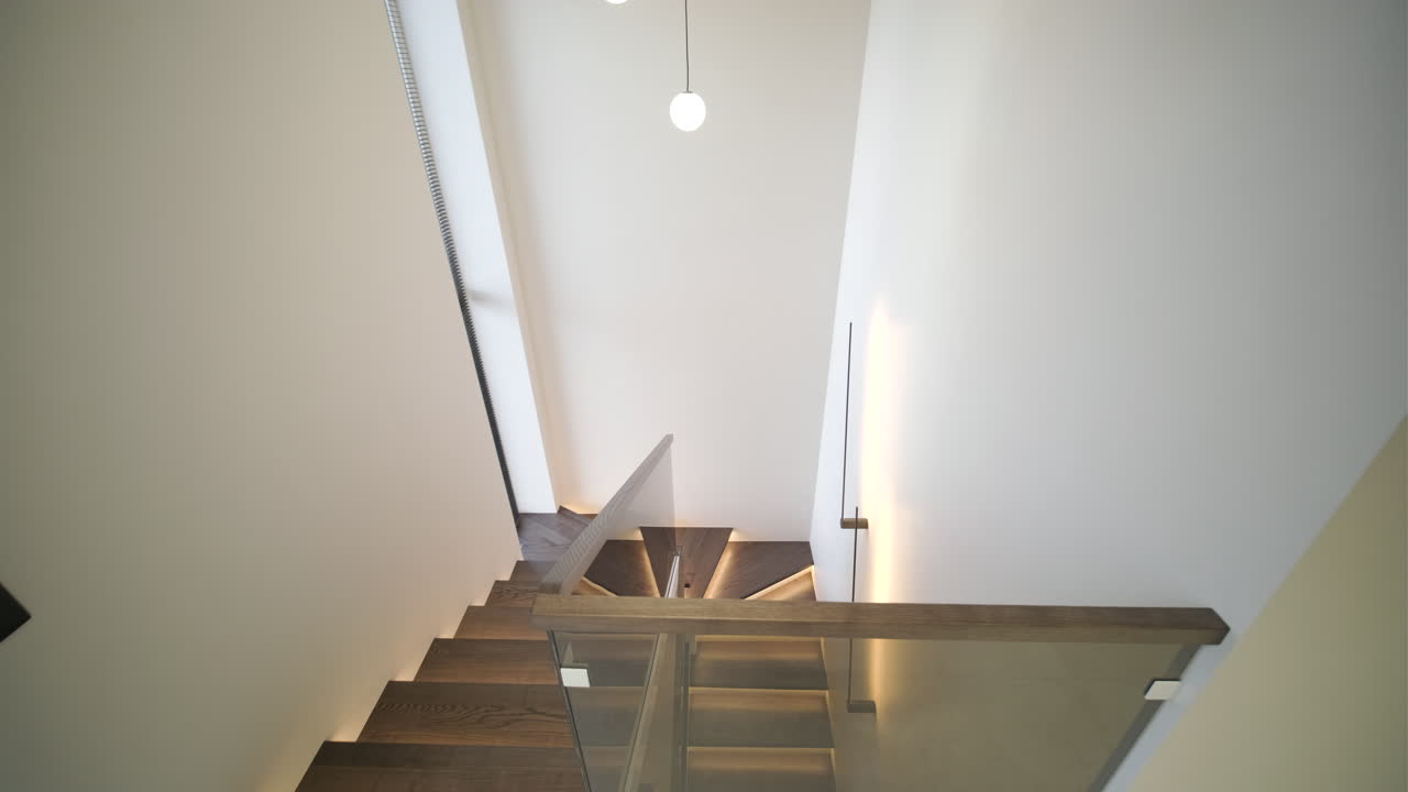 Scala moderna elegante con gradini in legno e ringhiera in vetro