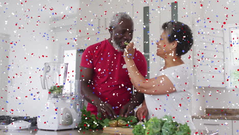 confetti falling against african american senior woman feeding chopped fruits to her husband