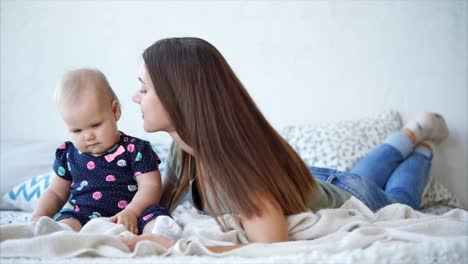 mother kissing her baby girl on the bed