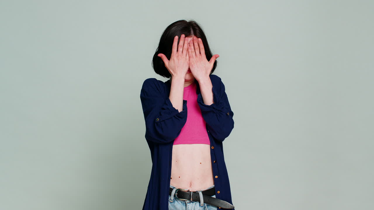Woman covering eyes and face with hand refusing to look expressing horror shock disgust reaction