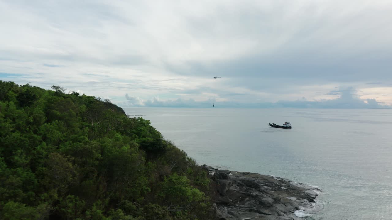 그물에서 섬으로 매달린 물품을 배달하기 위해 바지선에서 멀리 날아가는 헬리콥터