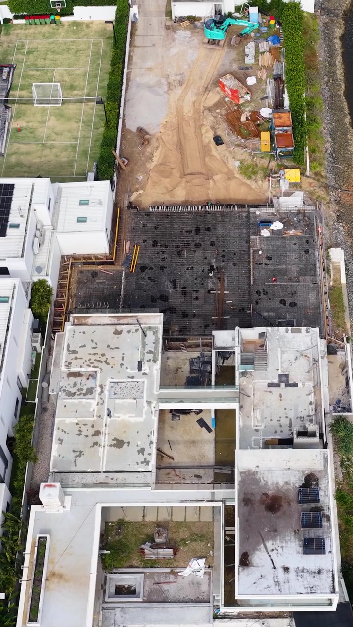 Vista cenital de dron revela viviendas de lujo junto al canal y construcción residencial activa en Gold Coast