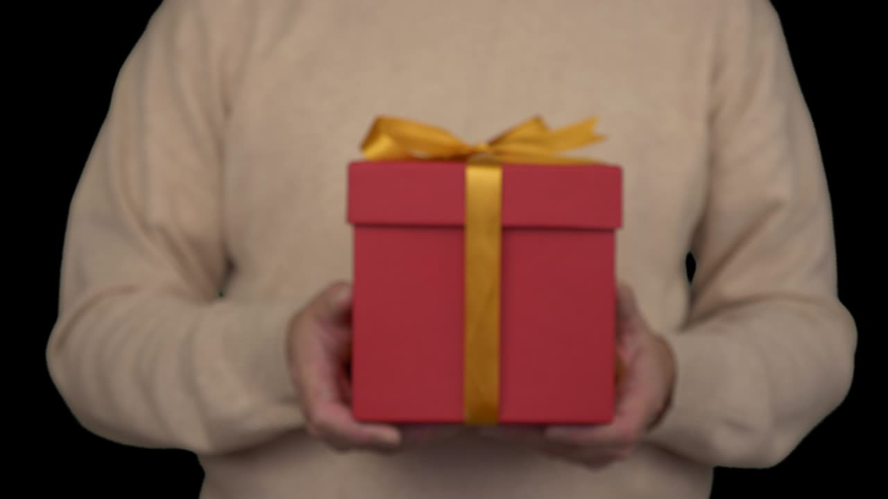hombre caucásico en suéter beige está sosteniendo una caja de regalos en las manos. vista frontal de hombre en suéter beige casual. hombre da un regalo. canal alfa clave de croma fondo transparente. cerrado. de desenfocado.