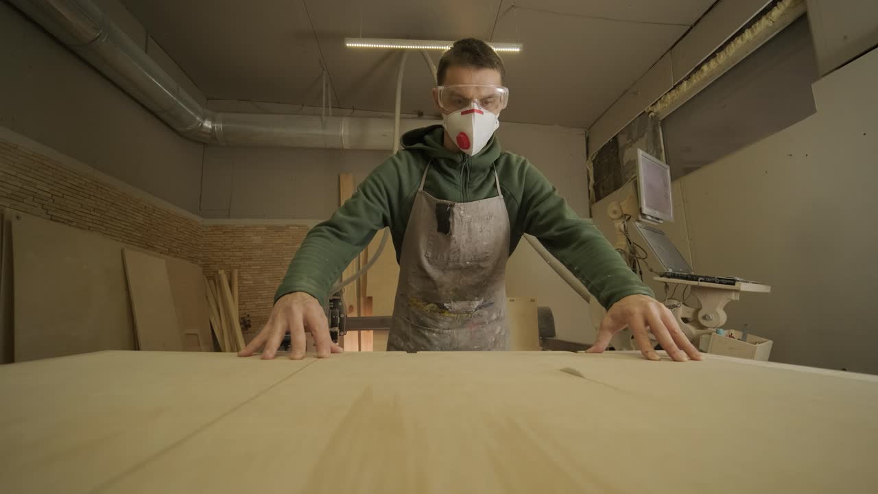 Woodworker cuts wooden plank, plywood panel, wood raw in the workshop using cutting machine