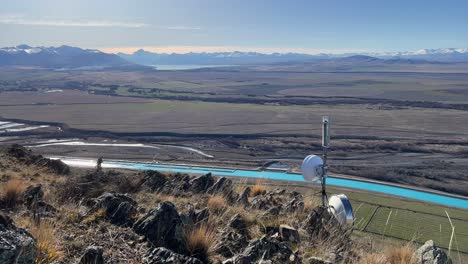 Vista-De-ángulo-Alto-De-Un-Canal-Hidroeléctrico-Y-Montañas-Nevadas-En-Nueva-Zelanda