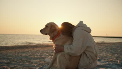 blonde girl petting her dog on the beach in the morning. sunny morning, beautiful transfusion of sunlight