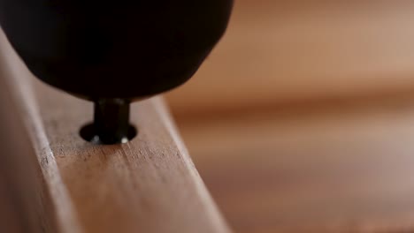 detailed view of a screw being driven into wood using an electric drill, highlighting precision and craftsmanship