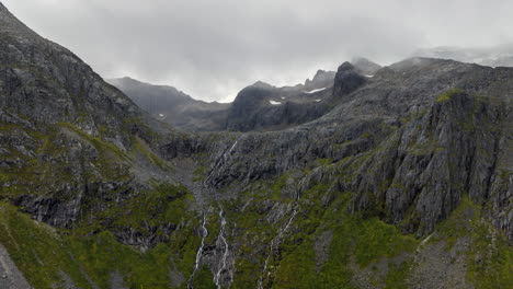 Panorámica-Hiper-Lapso-Escarpada-Cima-De-La-Montaña-Cubierta-De-Nieve-Envuelta-Por-Nubes-Bajas