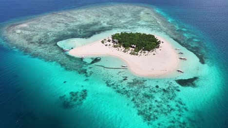 aerial view of patawan island in balabac, palawan, philippines featuring white sand beaches, turquoise waters, lush greenery, coral reefs, and several boats anchored along the pristine shoreline