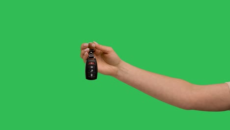 female hand holding car remote control points his finger at it and makes thumb up recommendation gesture. remote control car door lock against background green screen chroma key. slow motion. close up