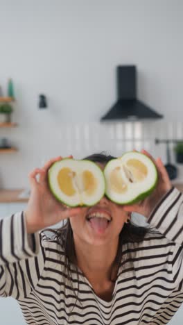 woman holding pomelo slices in a kitchen